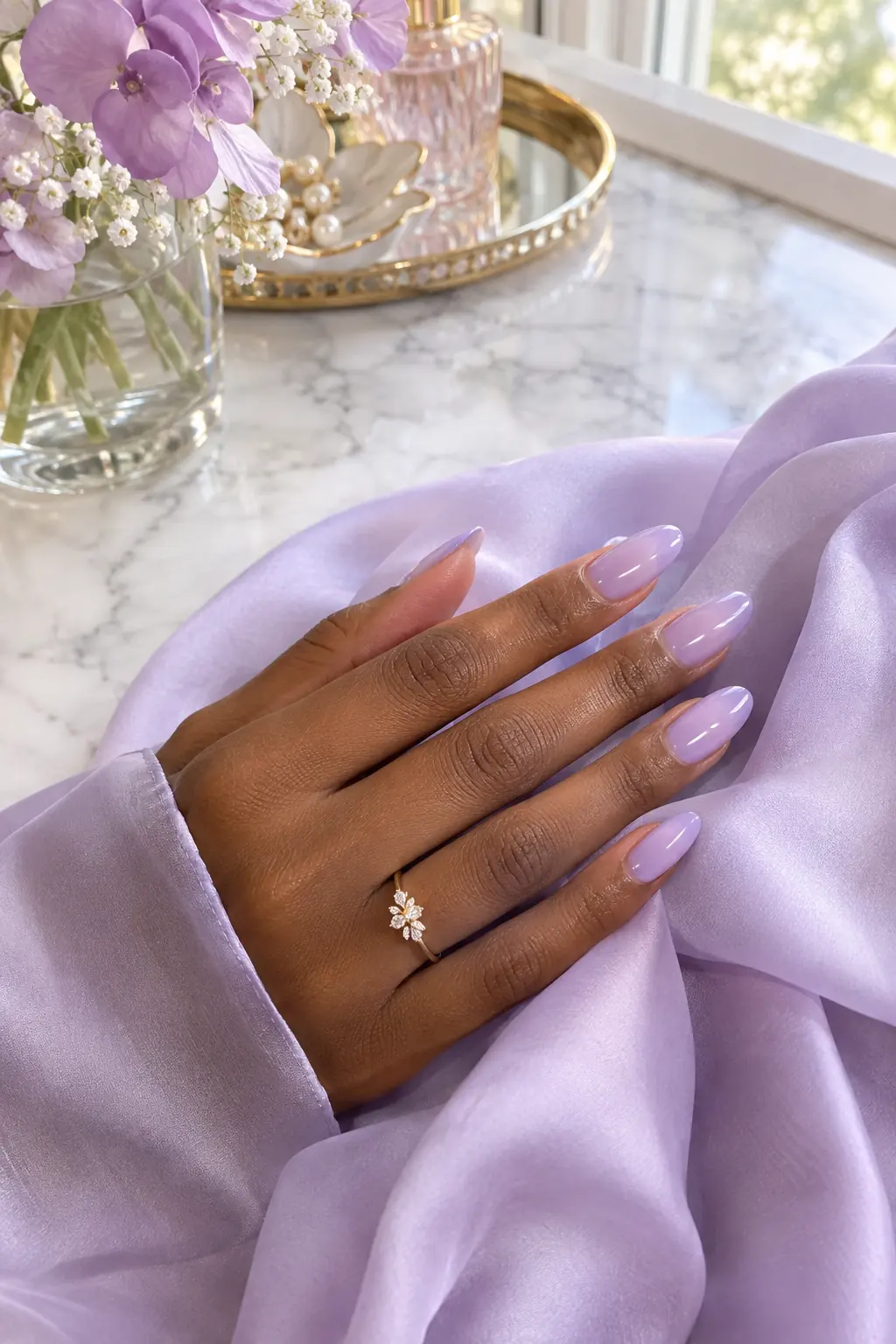 Sheer lavender jelly nails on deep skin with a lilac silk scarf on a marble vanity